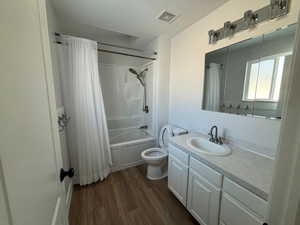 Full bathroom featuring hardwood / wood-style flooring, toilet, vanity, and shower / tub combo