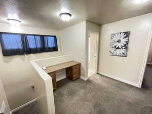 Unfurnished office with dark carpet and a textured ceiling