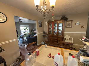 Dining space with a textured ceiling, hardwood / wood-style flooring, and a notable chandelier