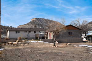 Rear view of house featuring a deck with mountain view. Backyard is fully fenced.