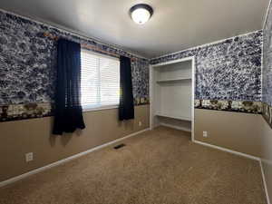 Unfurnished bedroom featuring carpet flooring, a textured ceiling, and a closet