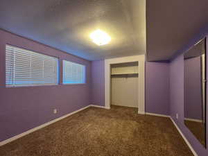 Unfurnished bedroom featuring a closet, a textured ceiling, and carpet flooring