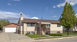 View of front facade featuring an outdoor structure, a garage, a chimney, central AC, and a shingled roof