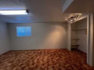 Unfurnished bedroom with track lighting, a closet, and carpet