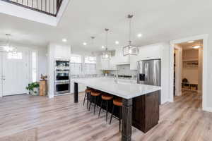 Kitchen with backsplash, a kitchen island with sink, and hanging light fixtures