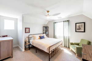 Bedroom with ceiling fan, light carpet, and vaulted ceiling