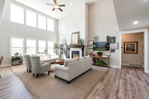 Living room with light hardwood / wood-style floors, ceiling fan, and a towering ceiling