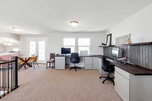 Office area featuring light colored carpet, french doors, and an inviting chandelier