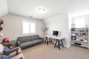 Office space with light carpet and vaulted ceiling