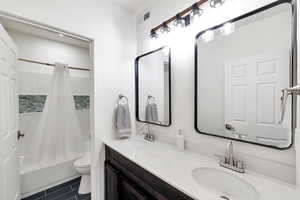 Full bathroom featuring toilet, tile patterned flooring, shower / bath combo, and vanity