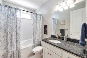 Full bathroom featuring toilet, vanity, and shower / tub combo with curtain