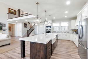 Kitchen featuring a center island with sink, appliances with stainless steel finishes, decorative backsplash, light hardwood / wood-style flooring, and dark brown cabinetry