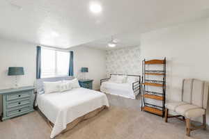 Carpeted bedroom featuring ceiling fan and a textured ceiling