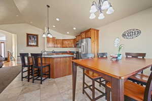 Tiled dining area featuring an inviting chandelier, lofted ceiling, and sink