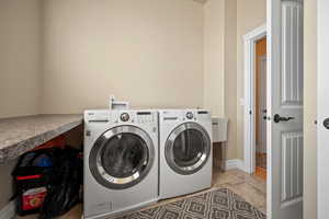 Laundry room featuring light tile patterned floors and washing machine and clothes dryer