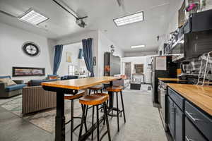 Kitchen featuring range with electric cooktop, butcher block countertops, and stainless steel refrigerator