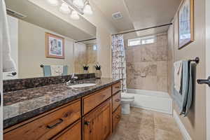 Full bathroom featuring toilet, a textured ceiling, vanity, and shower / tub combo with curtain