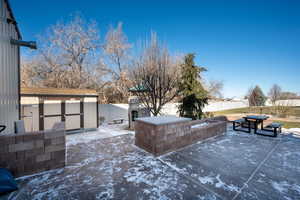 View of patio featuring a storage shed and an outdoor fireplace