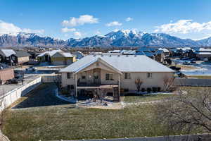 Rear view of house with a mountain view and a lawn