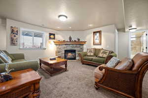 Living room with a textured ceiling, carpet flooring, and a fireplace