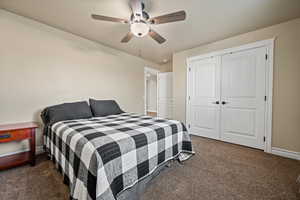 Carpeted bedroom with ceiling fan and a closet