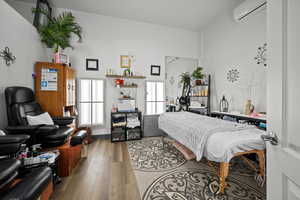 Bedroom with light hardwood / wood-style floors and an AC wall unit