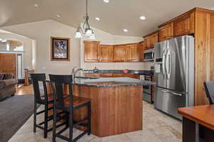 Kitchen featuring a kitchen island with sink, appliances with stainless steel finishes, sink, and a notable chandelier