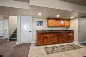 Kitchen featuring sink, light carpet, and dark stone counters