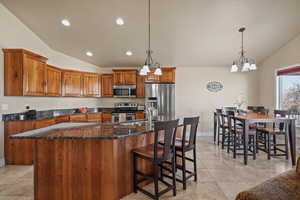 Kitchen with a spacious island, pendant lighting, appliances with stainless steel finishes, and lofted ceiling