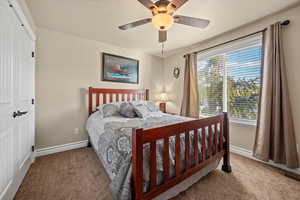 Carpeted bedroom with ceiling fan and a closet