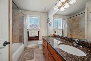 Full bathroom with toilet, vanity, tile patterned flooring, and plenty of natural light