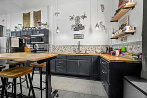 Kitchen featuring wooden counters, pendant lighting, sink, a kitchen breakfast bar, and stainless steel appliances