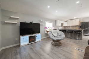 Living room with lofted ceiling, sink, and light hardwood / wood-style flooring