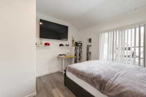 Bedroom with lofted ceiling and hardwood / wood-style floors