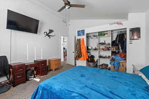 Carpeted bedroom with ceiling fan, a closet, and lofted ceiling