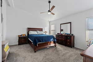 Carpeted bedroom with ceiling fan and vaulted ceiling