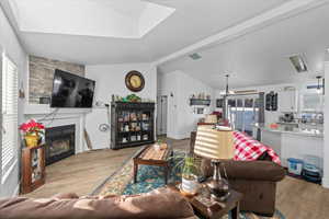 Living room featuring vaulted ceiling with beams, light hardwood / wood-style floors, sink, a fireplace, and a chandelier