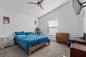 Bedroom featuring ceiling fan, dark colored carpet, and lofted ceiling