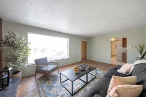 Living room with a textured ceiling and light hardwood  flooring