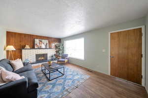 Living room featuring a textured ceiling, a fireplace, and hardwood flooring