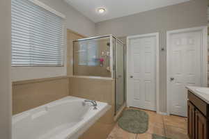 Bathroom featuring vanity, tile patterned floors, and plus walk in shower