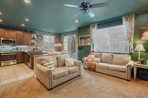 Carpeted living room with ceiling fan with notable chandelier