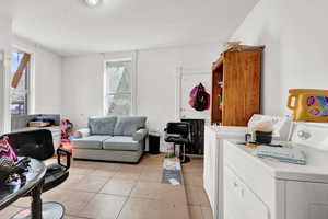 Living room featuring light tile patterned floors and washing machine and clothes dryer