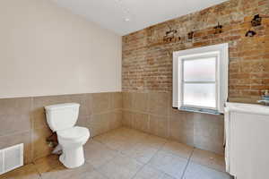 Bathroom with tile patterned floors, tile walls, toilet, and vanity