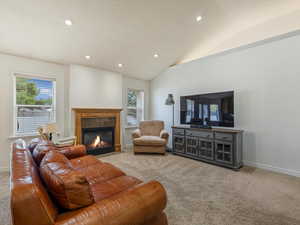 Carpeted living room featuring vaulted ceiling and a fireplace