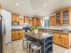 Kitchen with light tile patterned floors, custom exhaust hood, appliances with stainless steel finishes, a kitchen island, and sink