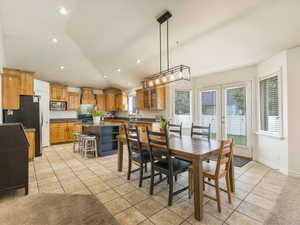 Tiled dining room with vaulted ceiling, sink, and french doors