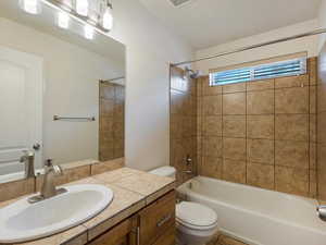 Full bathroom featuring toilet, tiled shower / bath, and vanity