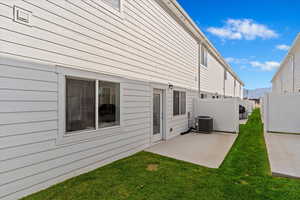 Rear view of property with central air condition unit, a yard, and a patio