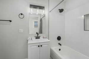 Bathroom with tiled shower / bath combo and vanity